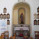 Di fronte a noi osserviamo una delle decorazioni sopravvissute: una statua di Santa Lucia posta su un altare in marmo, racchiusa in una nicchia in pietra e circondata da cornicette in legno con le tappe della Via crucis